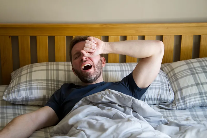 疲勞男性躺在床上睡眠不足